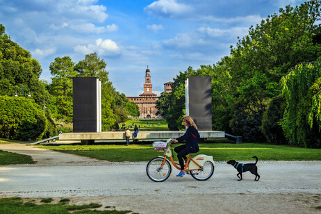 Una donna in bicicletta con il suo cane nei pressi di Parco Sempione a Milano @iStock.