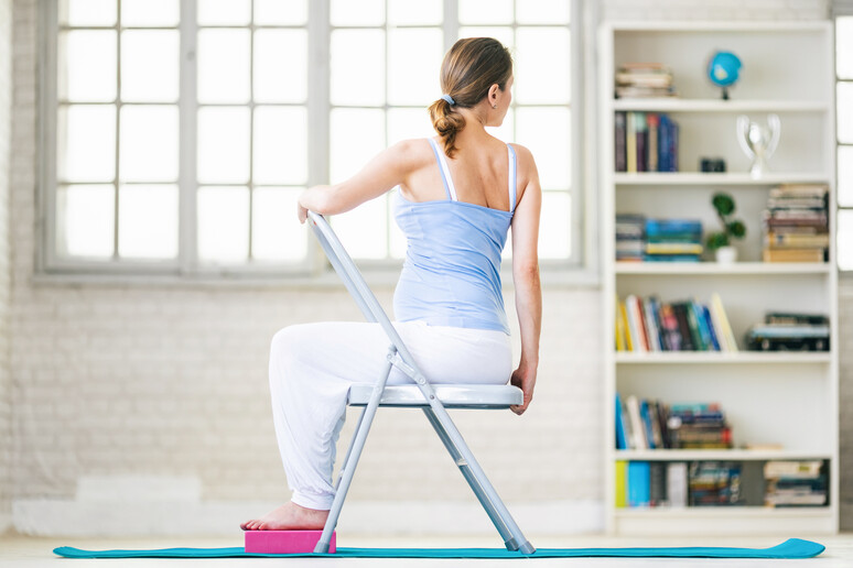 Una donna pratica lo yoga sulla sedia foto iStock. - RIPRODUZIONE RISERVATA